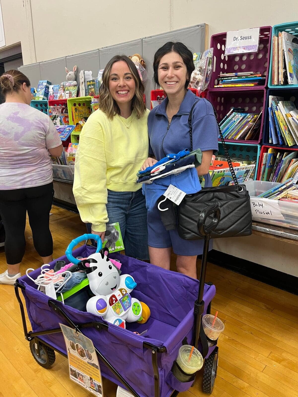 A mom holding a baby in a carrier showing off the clothes she has found