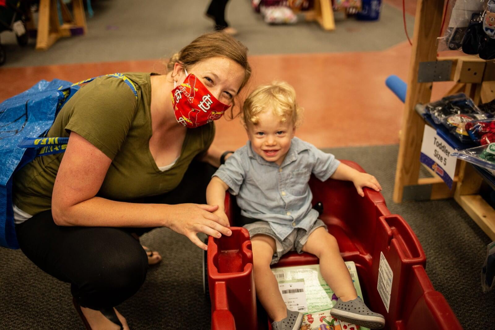 A mom with with her toddler son in a wagon shopping at JBF
